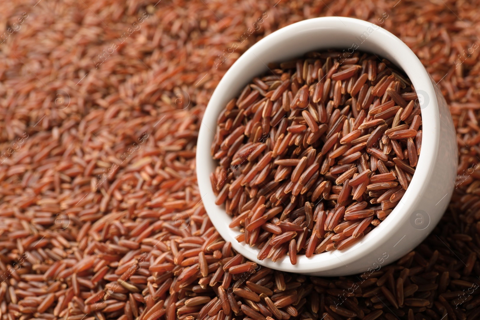 Photo of Ceramic bowl with raw brown rice on cereal