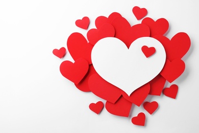 Composition with red hearts on white background, top view