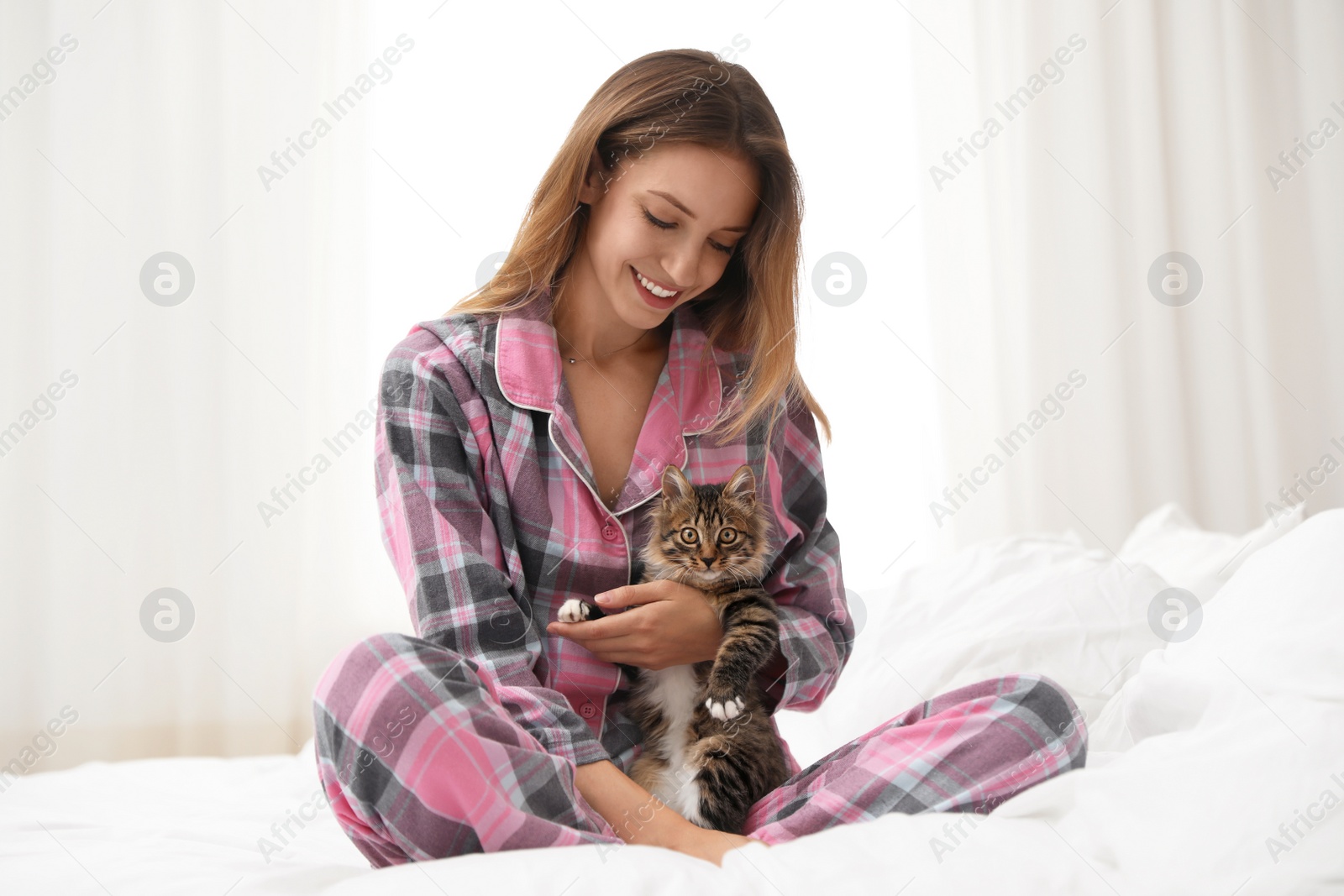 Photo of Woman with cat in bedroom. Owner and pet