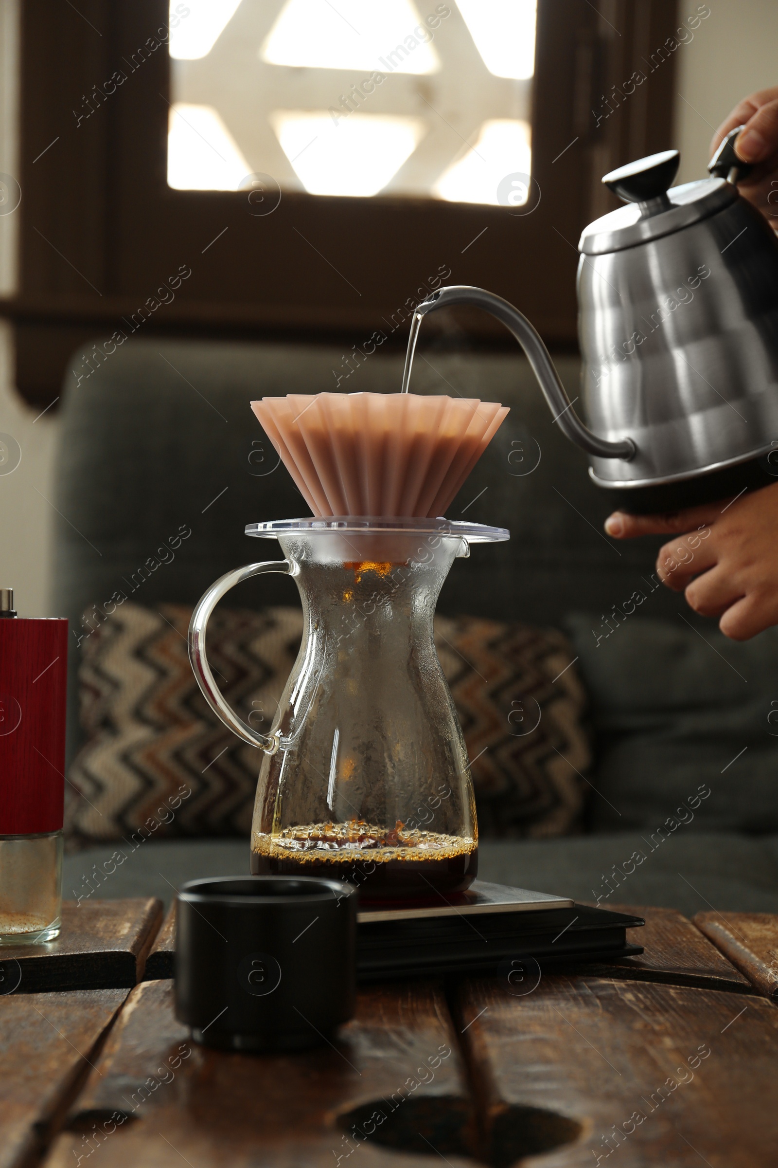 Photo of Barista preparing coffee at wooden table in cafe, closeup