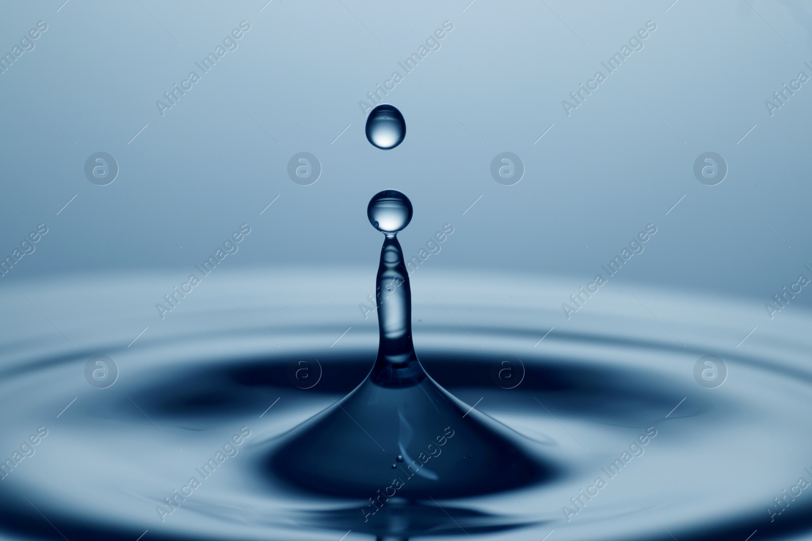 Photo of Splash of clear water with drops on light blue background, closeup