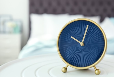 Stylish alarm clock on table in bedroom. Time to wake up