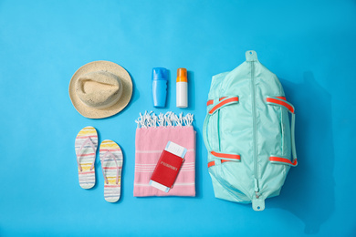 Photo of Flat lay composition with bag and travel accessories on blue background