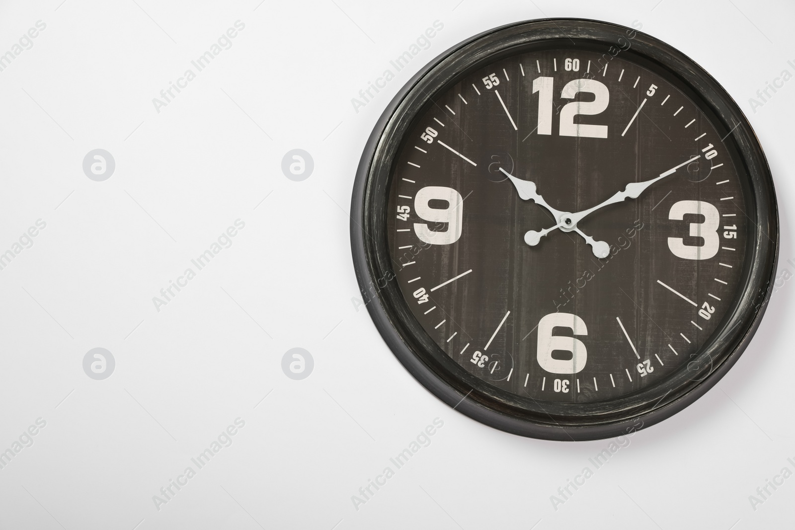 Photo of Stylish analog clock hanging on white wall, space for text