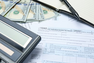 Photo of Calculator, pen, money and notebook on documents, closeup. Tax accounting