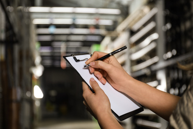 Woman with clipboard in wholesale warehouse, closeup