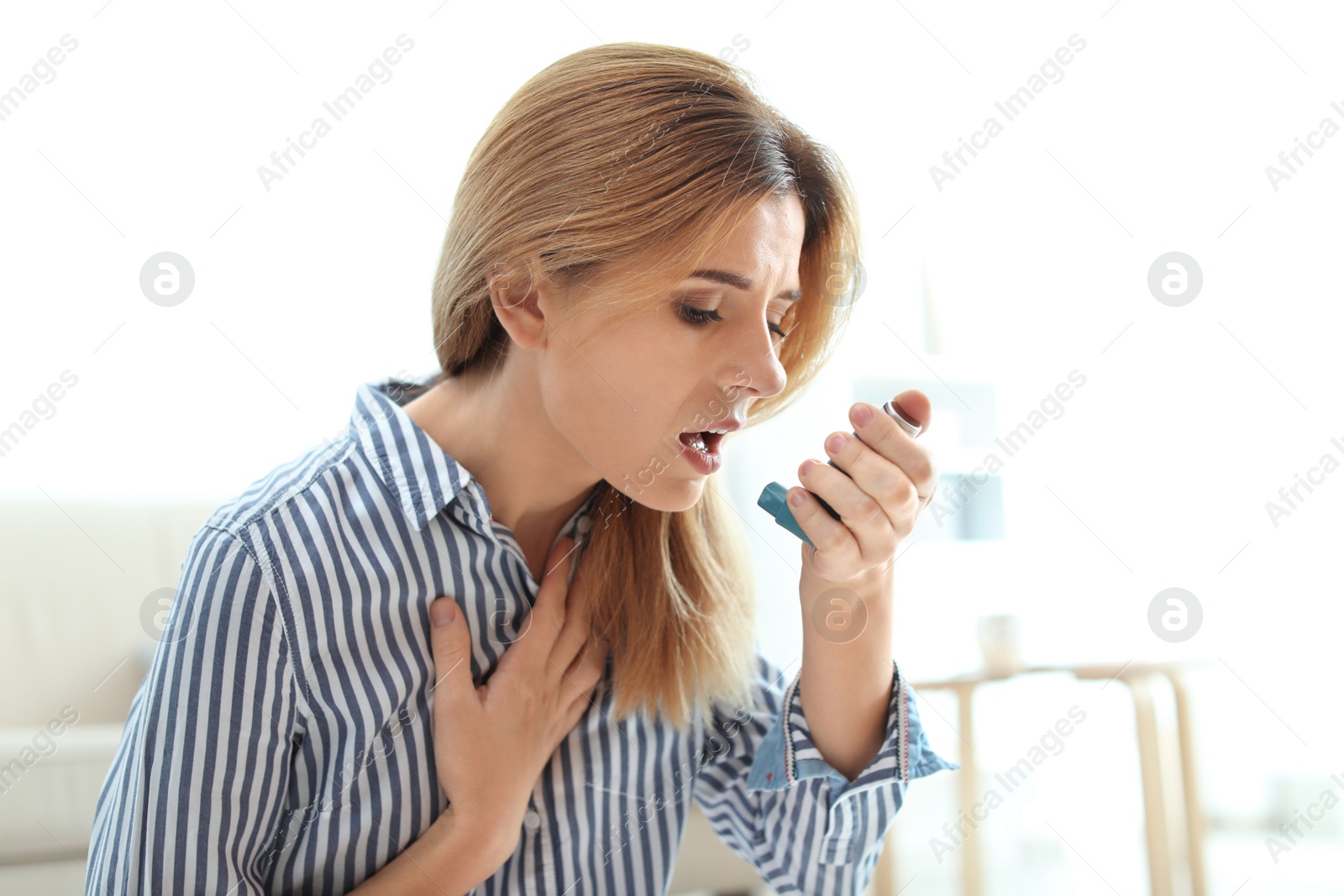 Photo of Woman using asthma inhaler at home. Health care