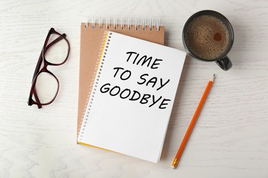 Image of Notebook with text Time to say goodbye, office stationery and cup of coffee on white wooden table, flat lay