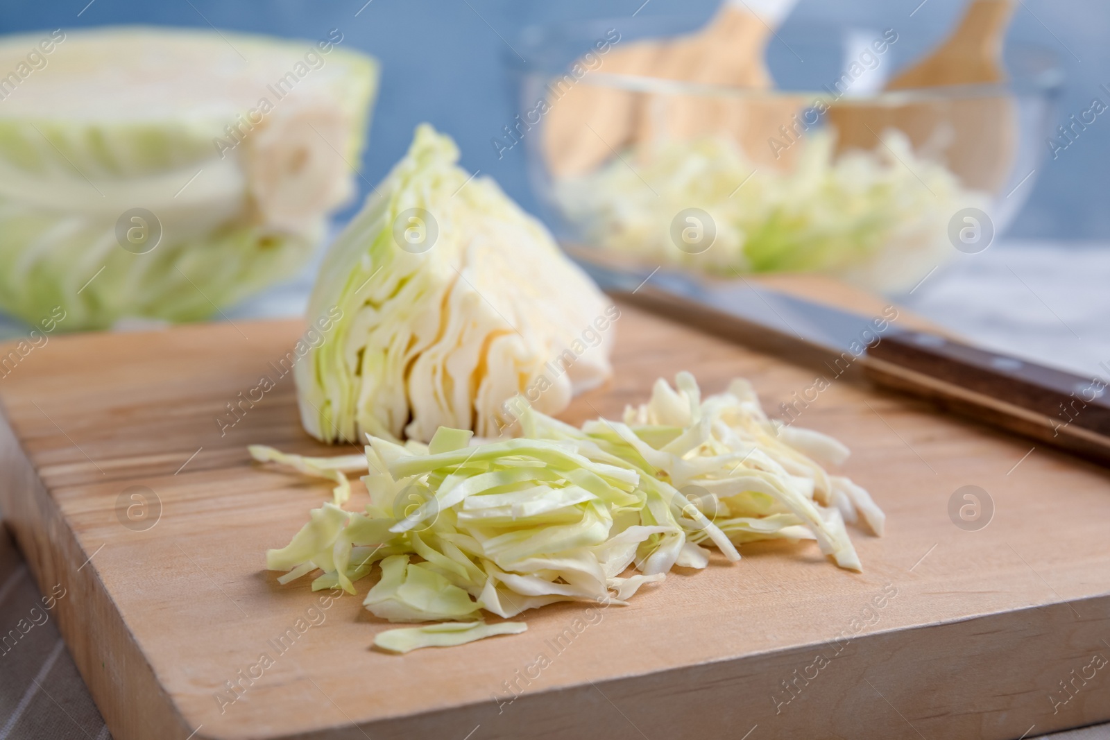 Photo of Wooden board with cut cabbage on table