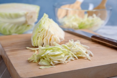 Wooden board with cut cabbage on table