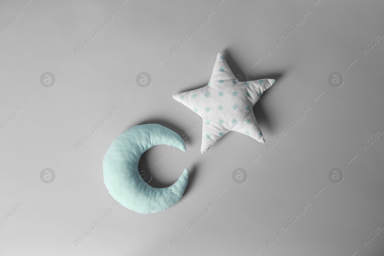 Photo of Soft decorative pillows in shape of moon and star on light background