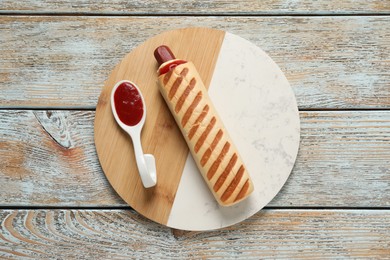 Delicious french hot dog and dip sauce on rustic wooden table, top view