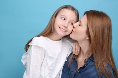 Portrait of mother and her cute daughter on light blue background