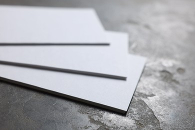 Blank business cards on grey textured background, closeup. Mockup for design