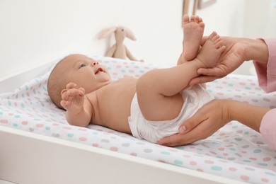 Photo of Mother changing her baby's diaper on table at home