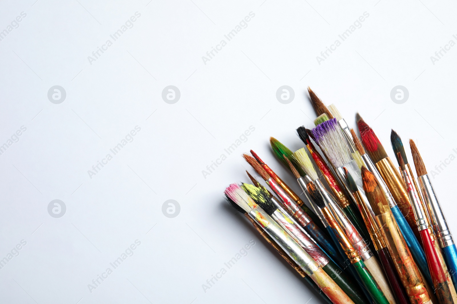 Photo of Different paint brushes on white background, top view with space for text