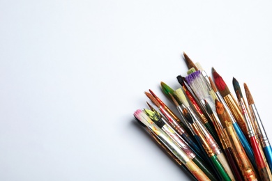 Photo of Different paint brushes on white background, top view with space for text