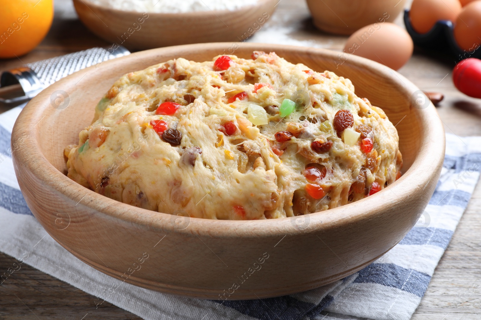 Photo of Raw dough with candied fruits and nuts for Stollen in bowl on wooden table, closeup. Baking traditional German Christmas bread