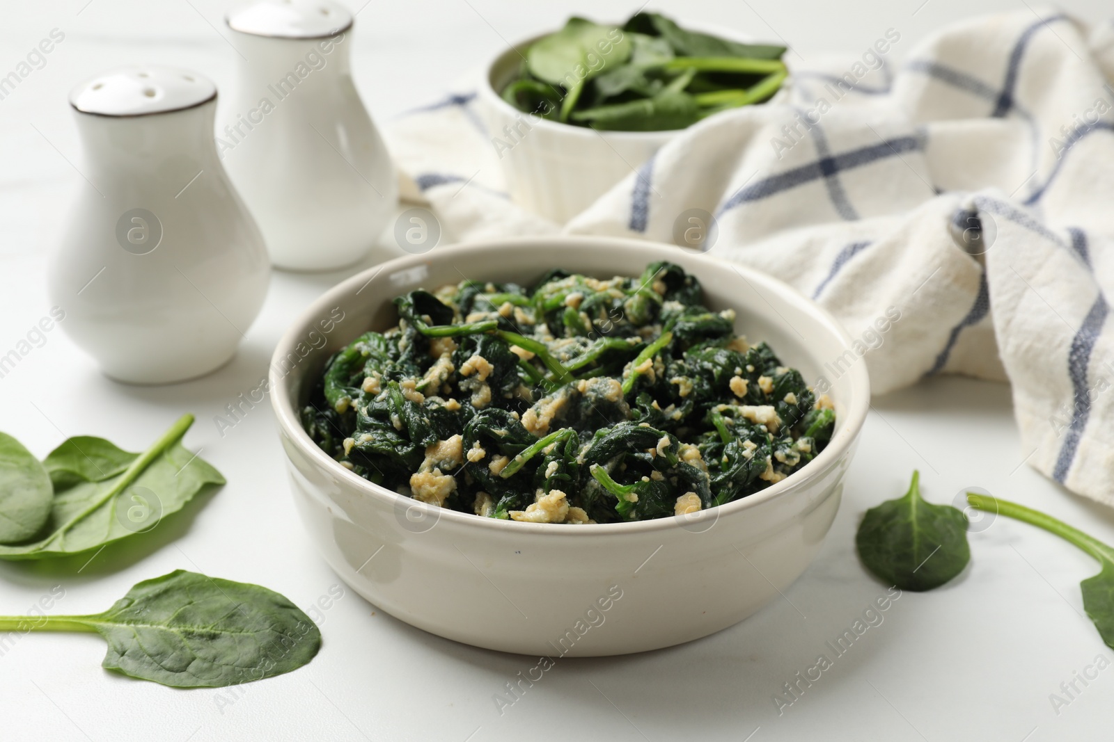 Photo of Tasty spinach dip with eggs in bowl on white table