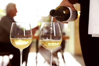 Waitress pouring wine into glass in restaurant, closeup