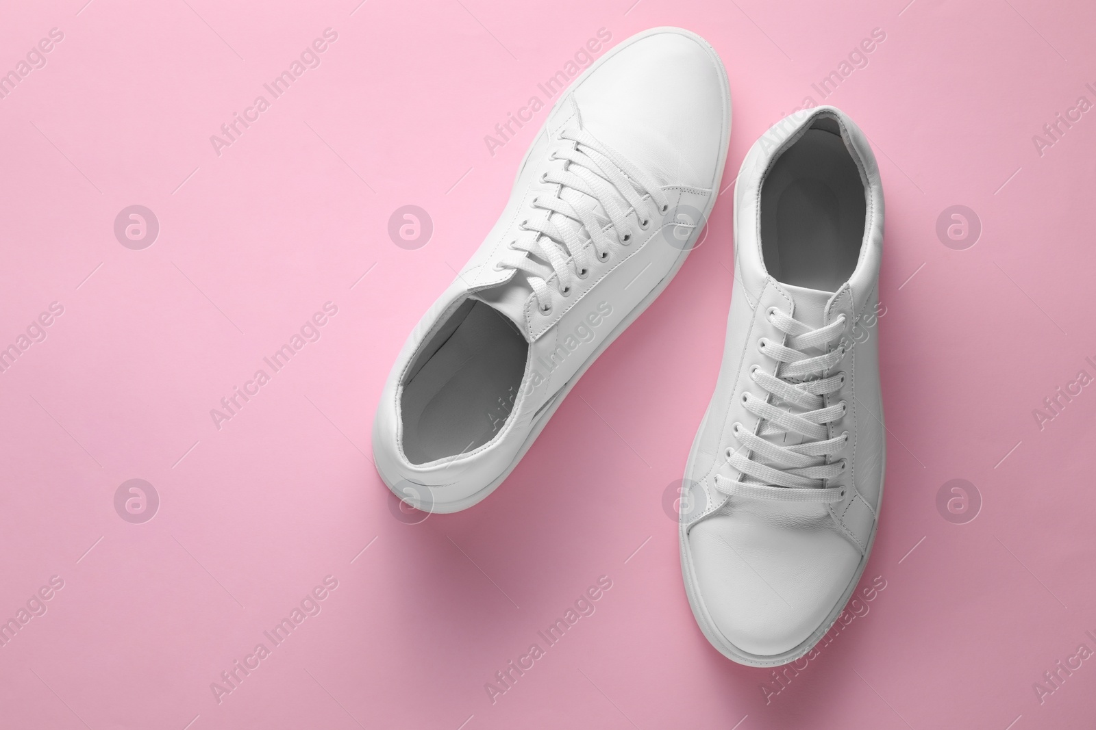 Photo of Pair of stylish white sneakers on pink background, top view. Space for text