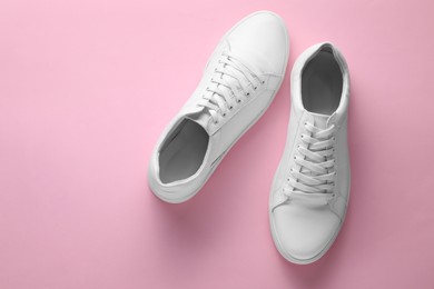 Pair of stylish white sneakers on pink background, top view. Space for text