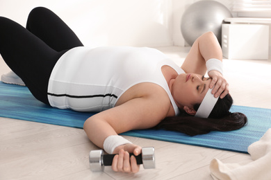 Photo of Lazy overweight woman resting instead of training on mat at gym