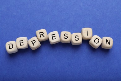 Photo of Word Depression made of wooden cubes on blue background, flat lay