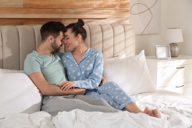 Photo of Happy couple in pajamas on bed at home