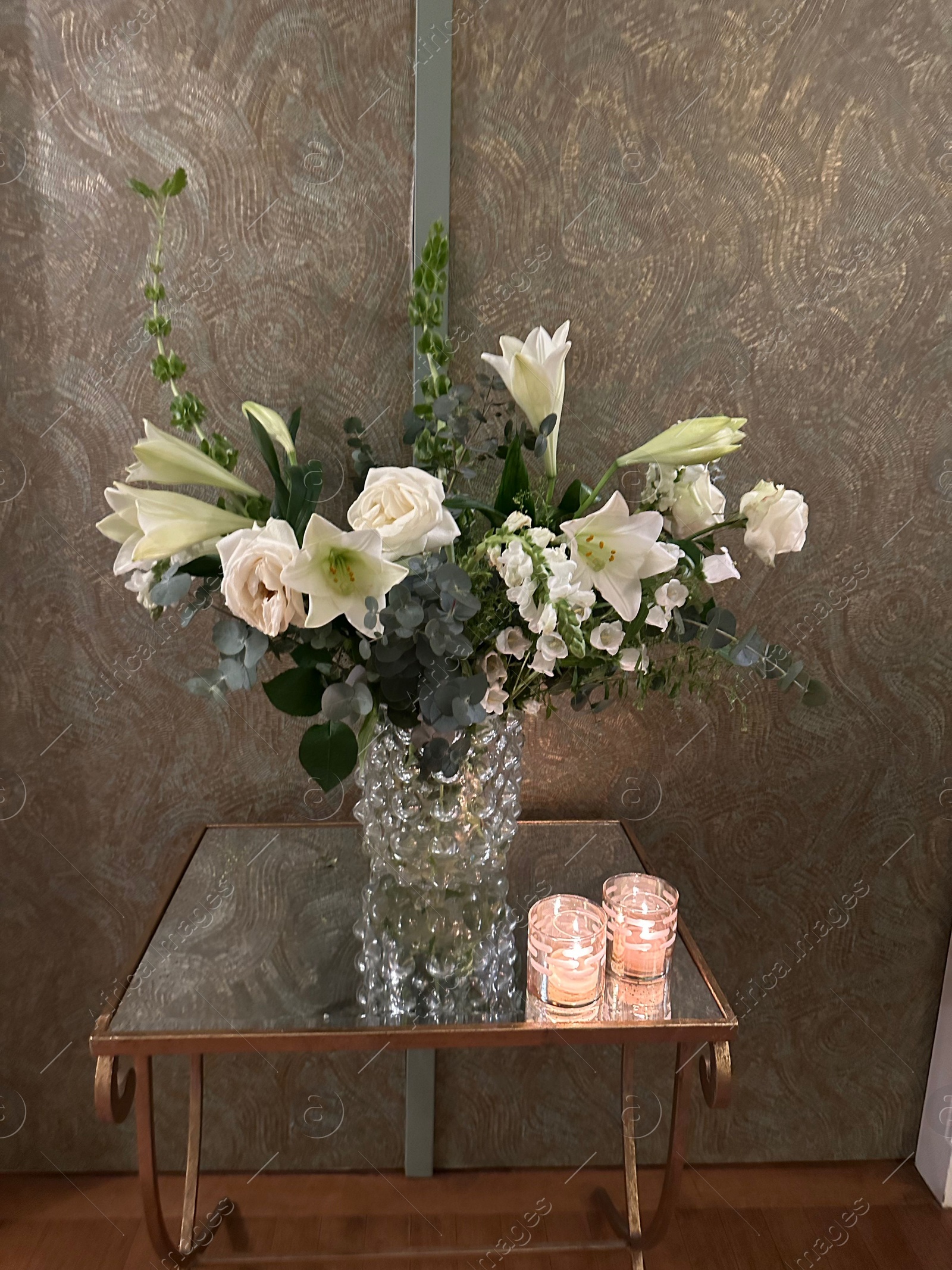 Photo of Beautiful flowers in vase and burning candles on table indoors