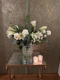 Photo of Beautiful flowers in vase and burning candles on table indoors