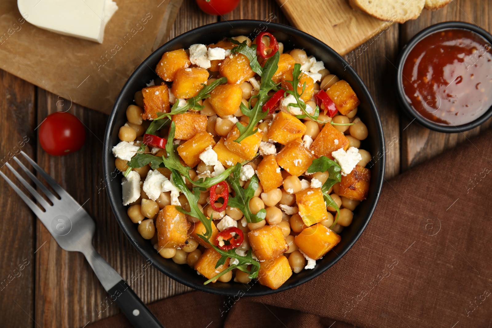 Photo of Delicious fresh chickpea salad served on wooden table, flat lay