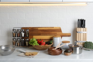 Different cooking utensils and fresh vegetables on countertop in kitchen