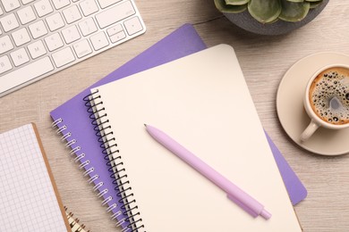 Flat lay composition with spiral notebooks, coffee and pen on wooden table