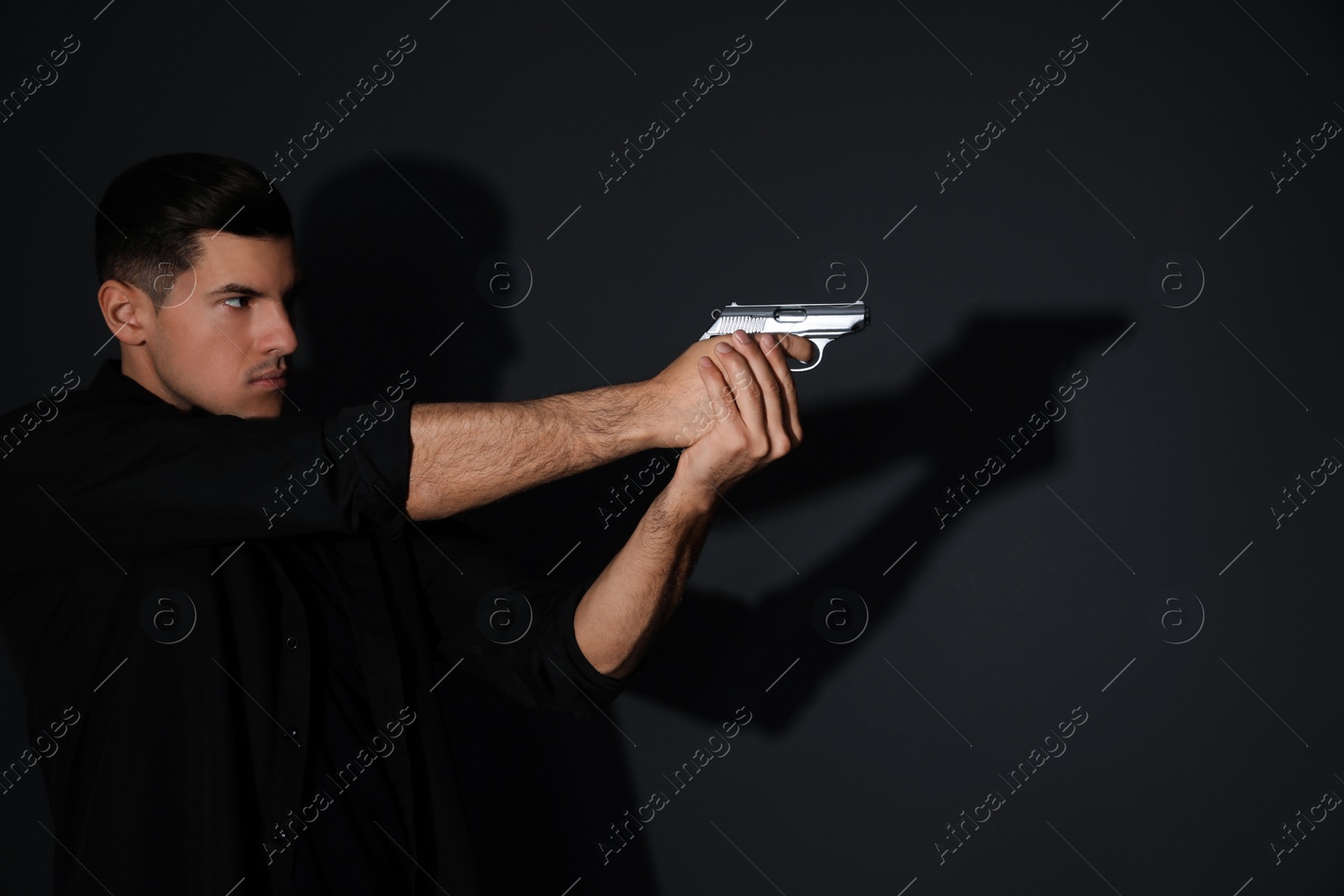 Photo of Professional killer with gun on black background