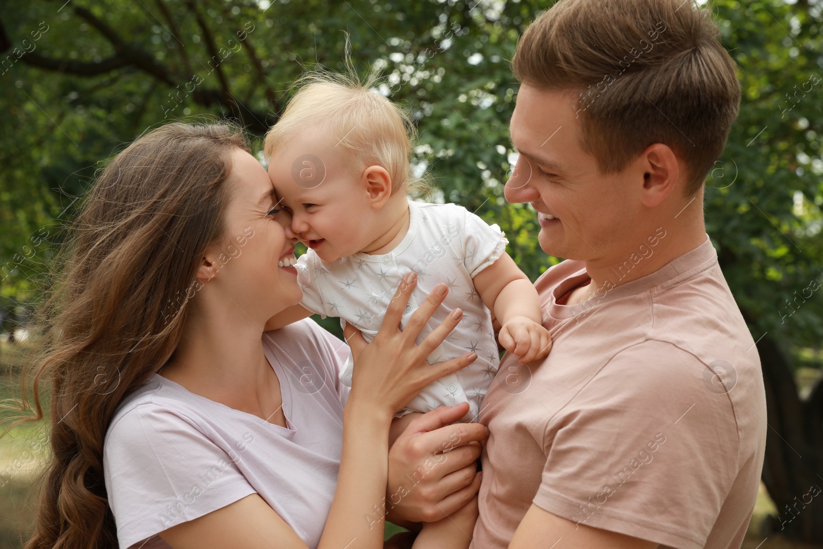 Photo of Parents with their cute baby spending time together outdoors. Happy family