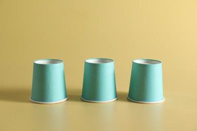Photo of Shell game. Three paper cups on yellow background
