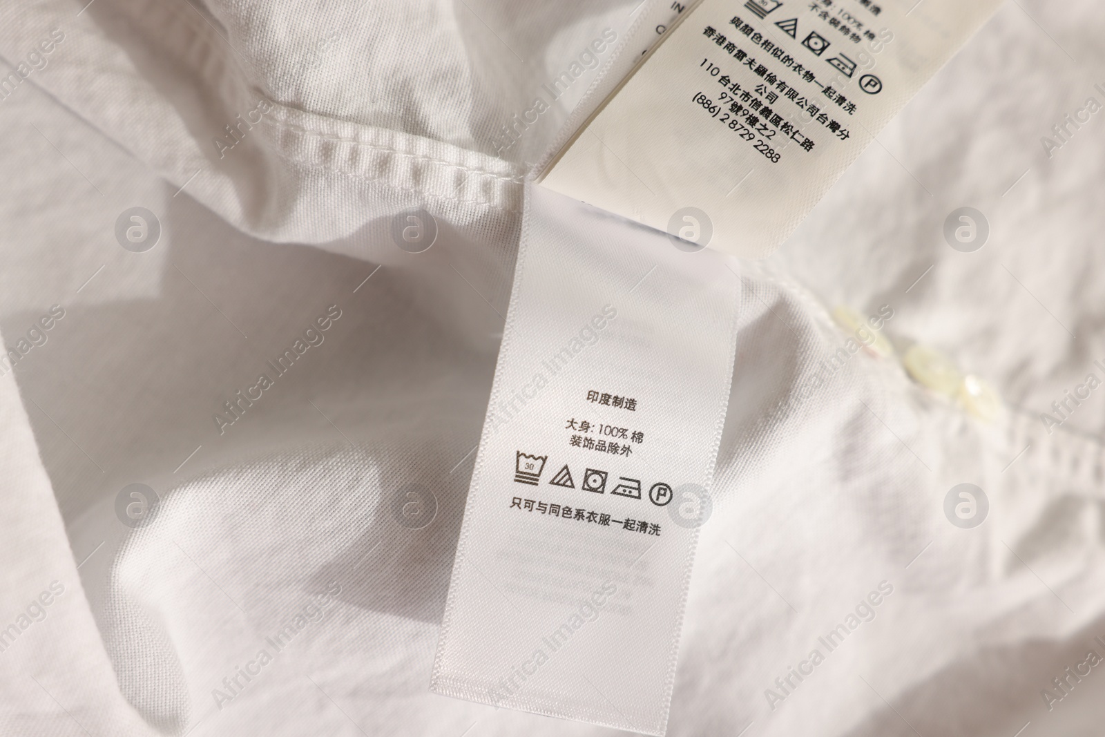 Photo of Clothing label in Chinese language on white garment, closeup