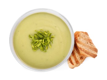 Photo of Bowl of delicious leek soup and croutons isolated on white, top view
