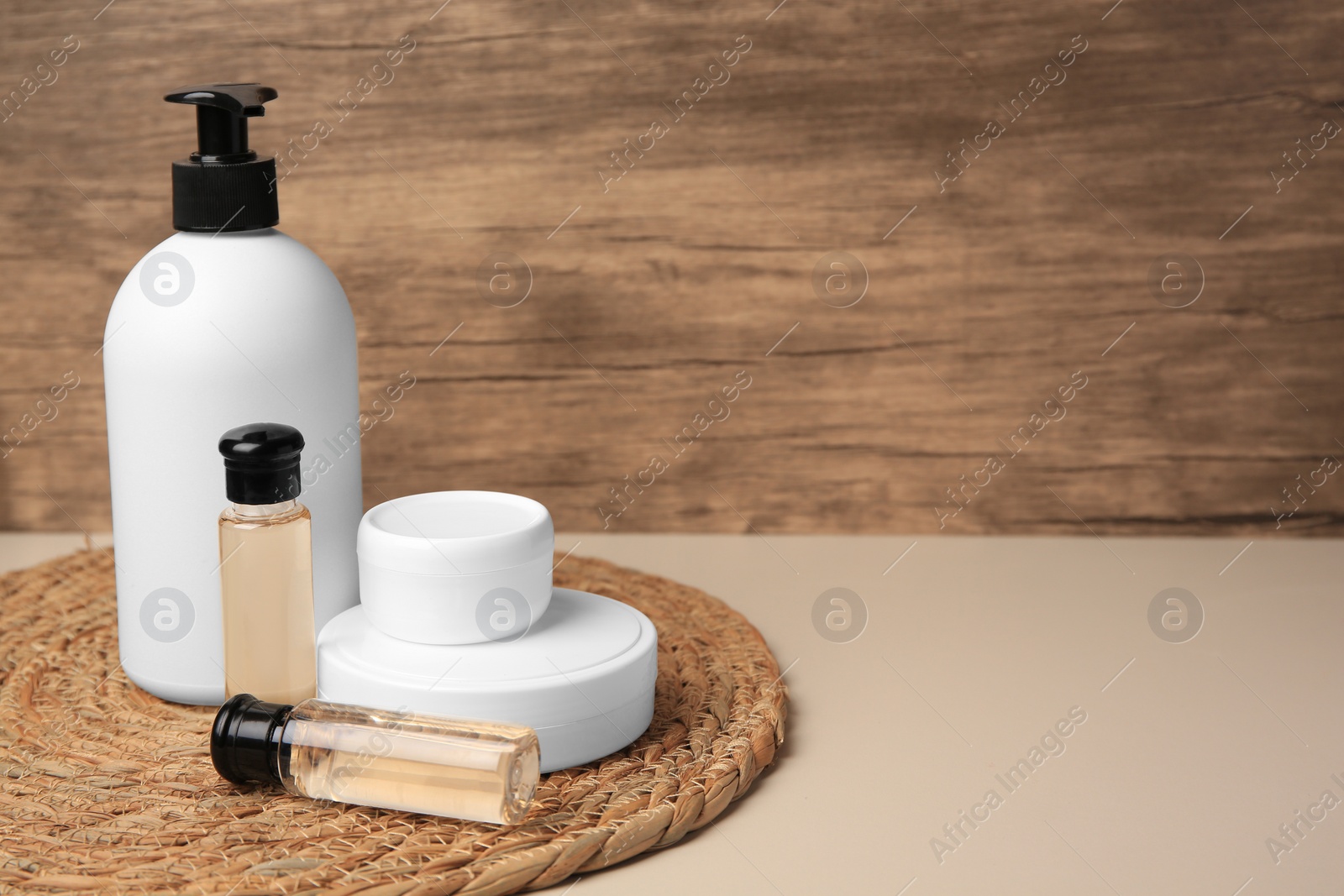 Photo of Bottles and jars of cosmetic products on beige table. Space for text
