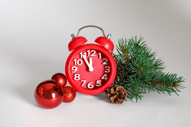 Photo of Alarm clock with Christmas decor on white background. New Year countdown