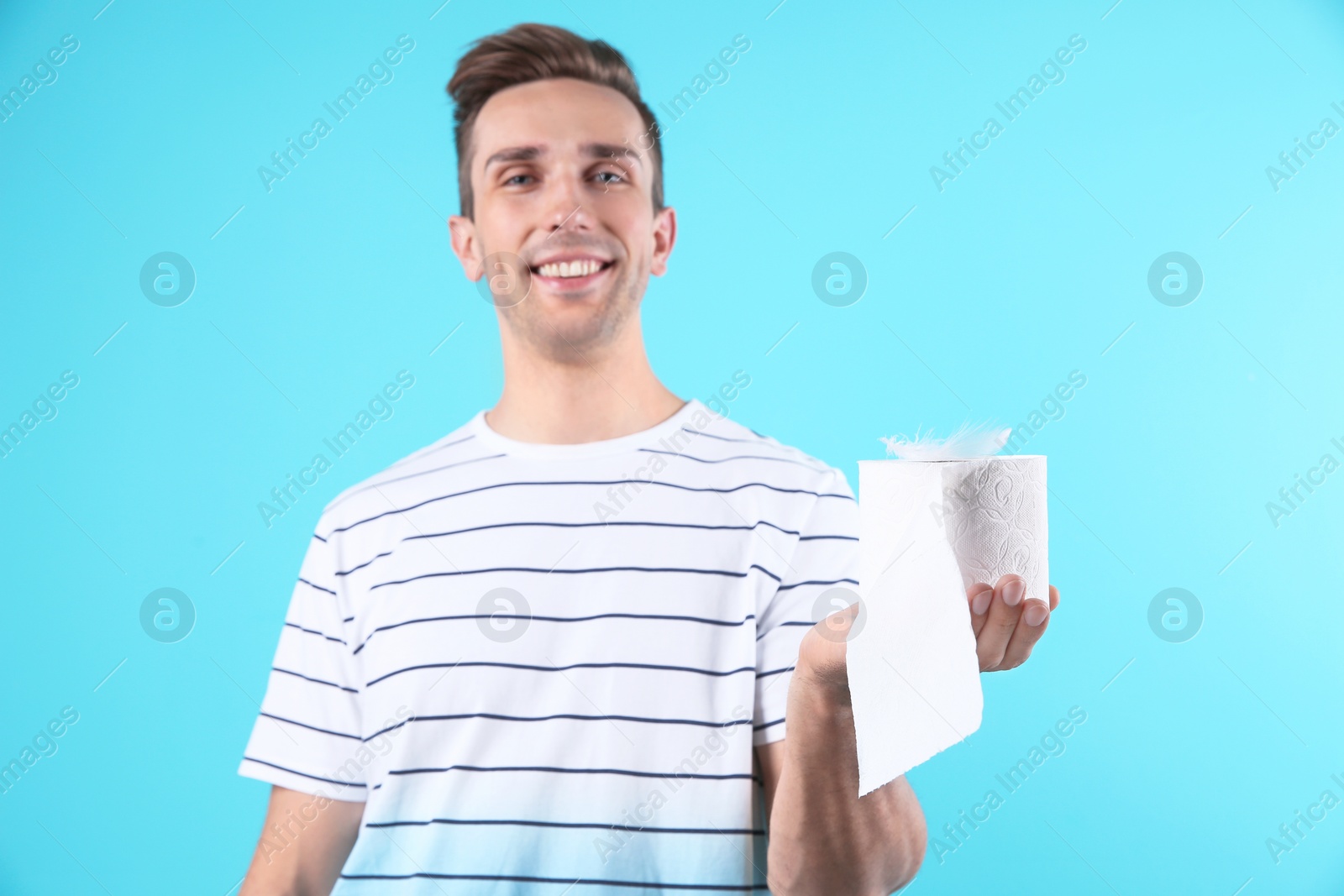 Photo of Young man holding toilet paper roll on color background