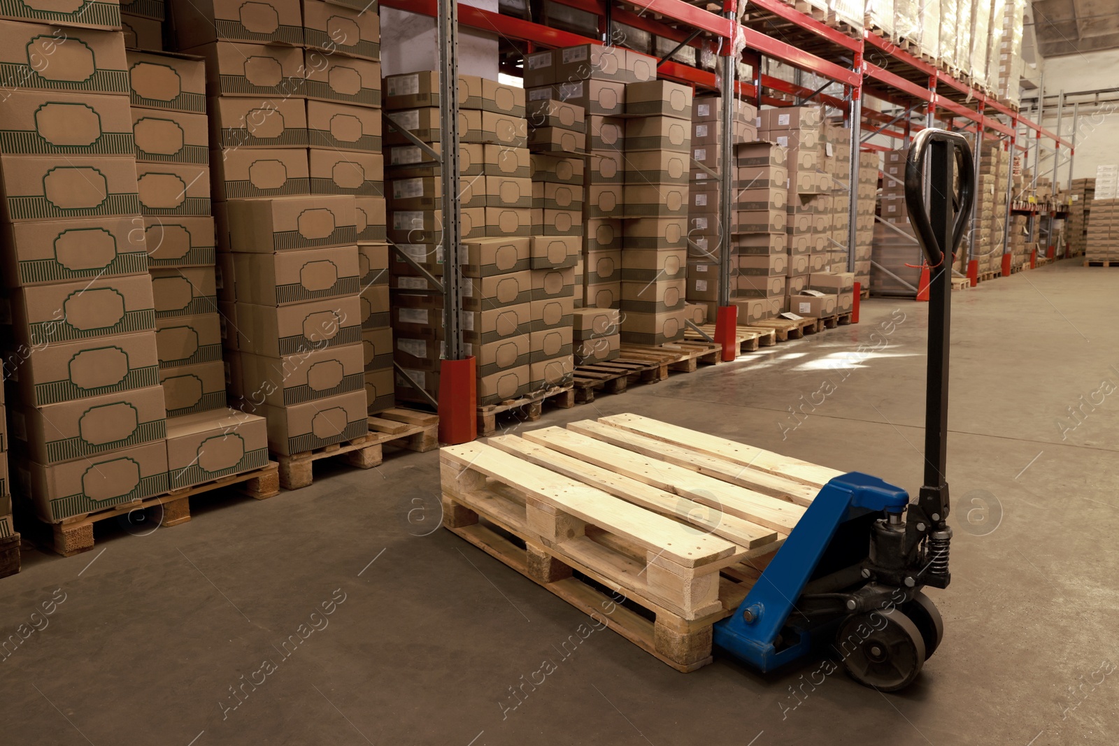 Image of Modern manual forklift with wooden pallets in warehouse