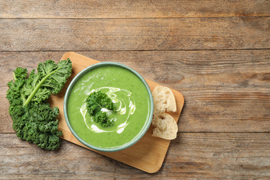 Tasty kale soup served on wooden table, flat lay. Space for text