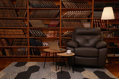 Photo of Cozy home library interior with leather armchair, laptop and collection of vintage books on shelves