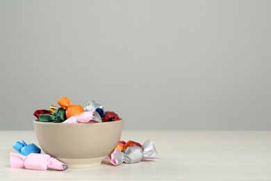 Photo of Candies in colorful wrappers on light table, space for text