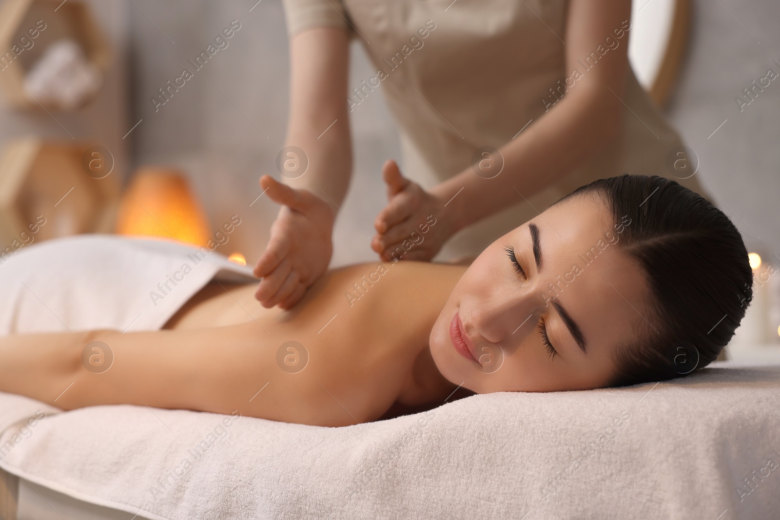 Photo of Woman receiving back massage on couch in spa salon