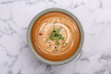 Photo of Delicious pumpkin soup with microgreens in bowl on white marble table, top view
