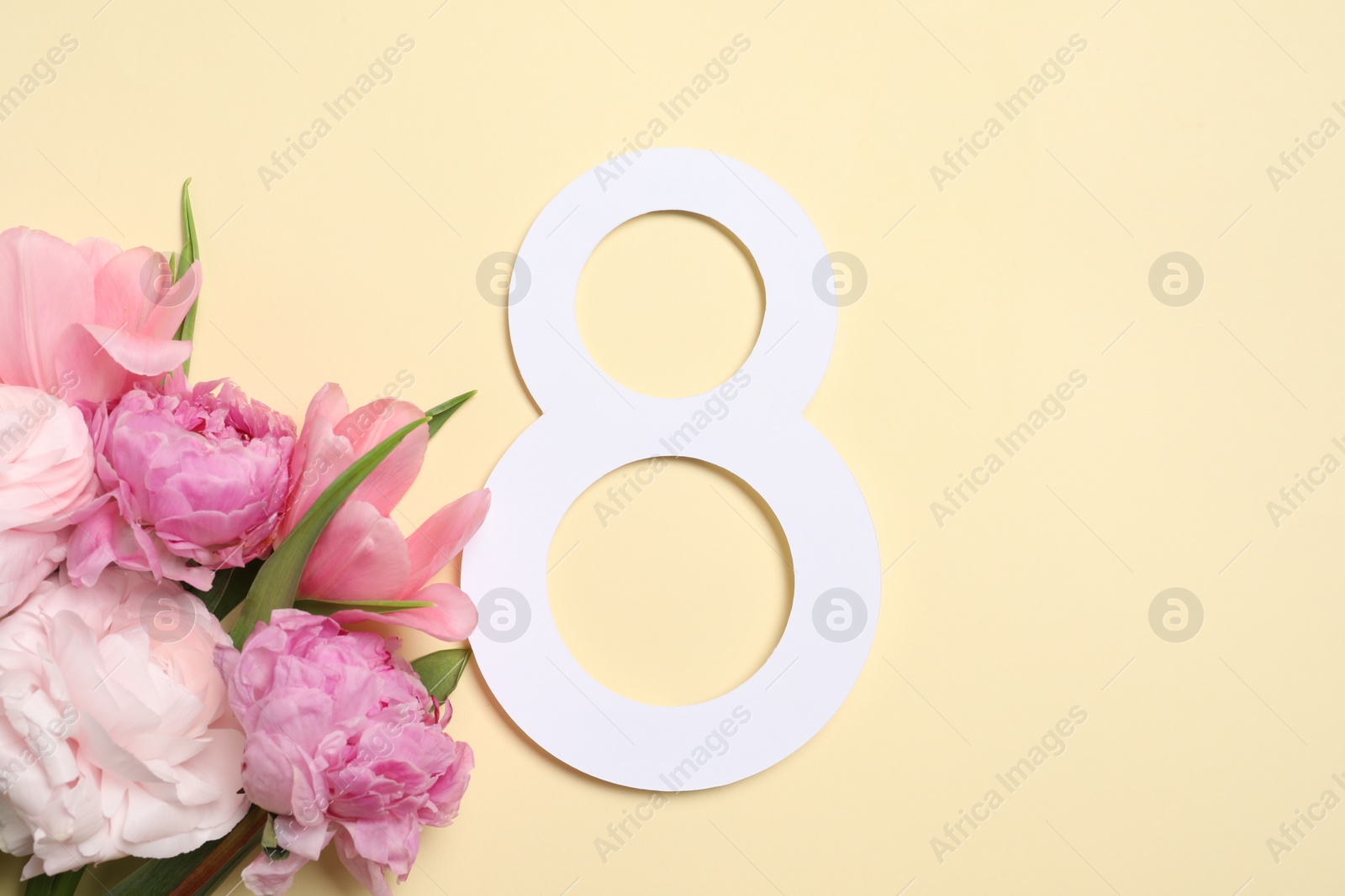 Photo of 8 March greeting card design with beautiful flowers on light yellow background, top view