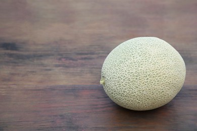 Photo of Whole ripe melon on wooden table. Space for text